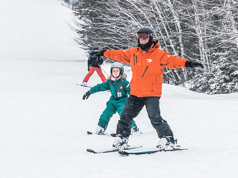 Un moniteur donne une leçon de ski à une jeune skieuse