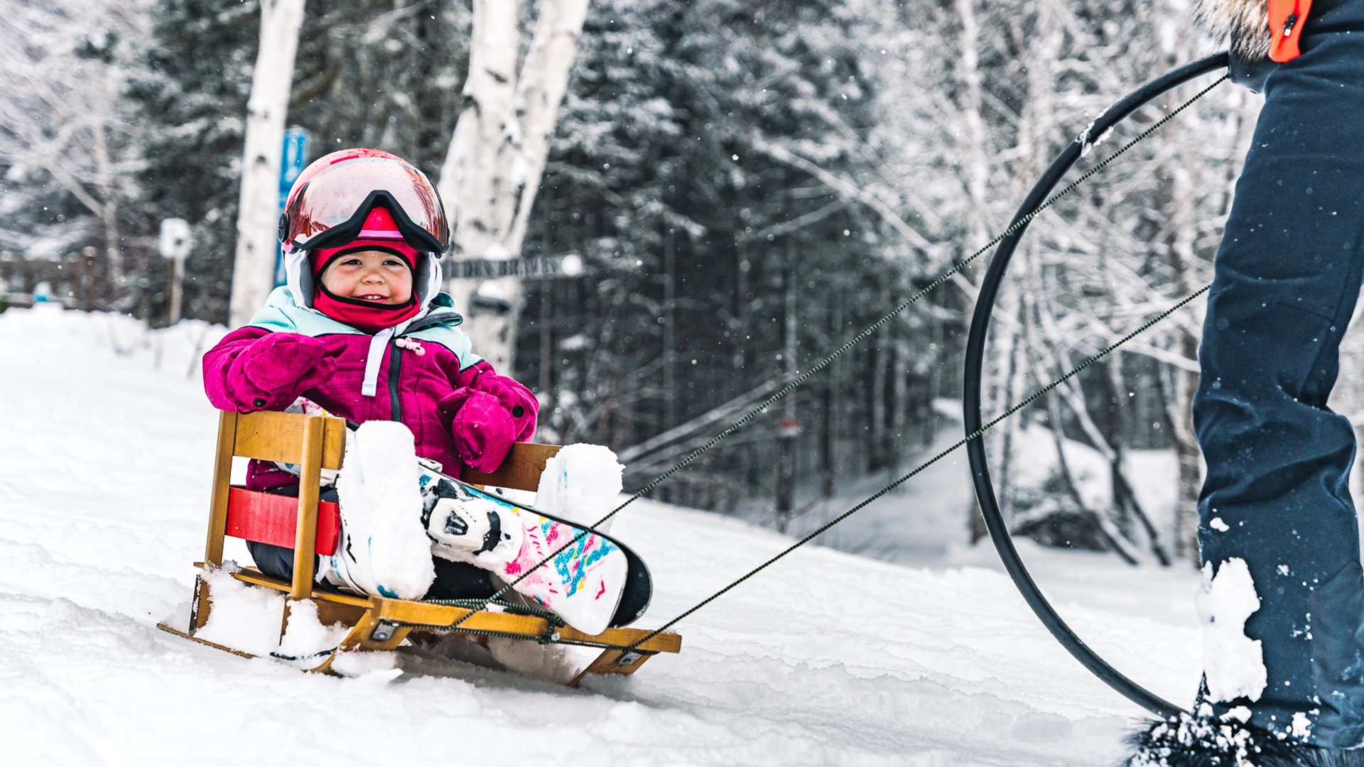 Une fillette assise dans un traineau avec ses skis