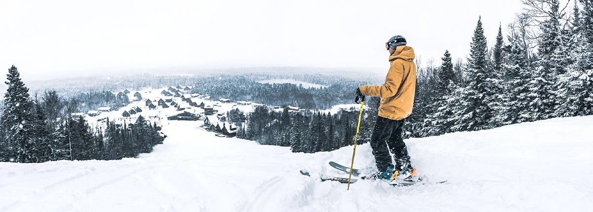 Un skieur observe le village alpin du Mont-Vidéo du haut des pentes dans une neige poudreuse non damée