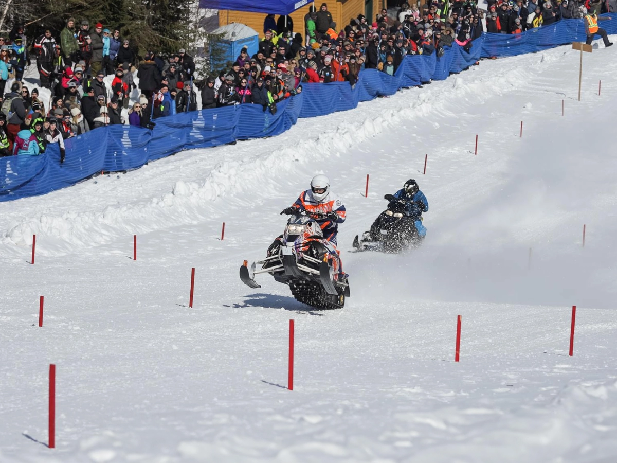Deux pilotes de motoneiges course sur la piste enneigée au bas d'une pente du Mont-Vidéo